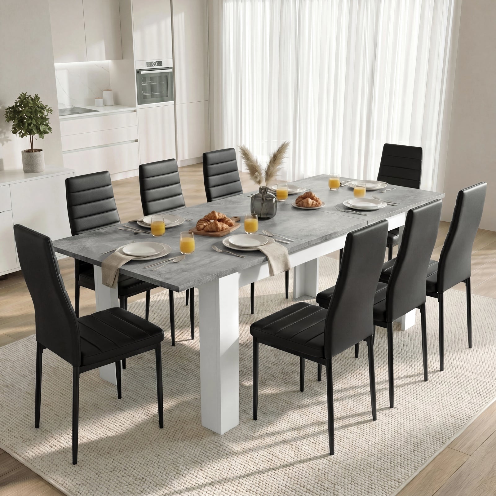 [Concrete] Extended concrete-effect dining table for 6-8 at breakfast; 8 black chairs surround its thick white legs.