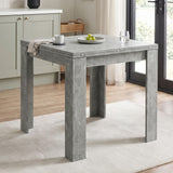 [Concrete] Closed square flip-top dining table styled with a mug, fruit bowl and glass in a bright kitchen.