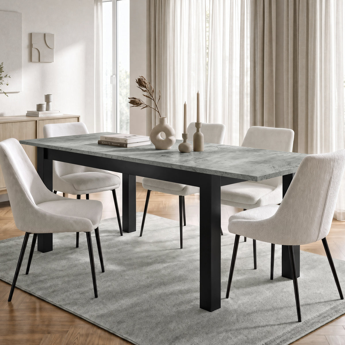 [160cm | Concrete] Extended table in bright dining room with six cream chairs, vases, candles, rug, and curtains