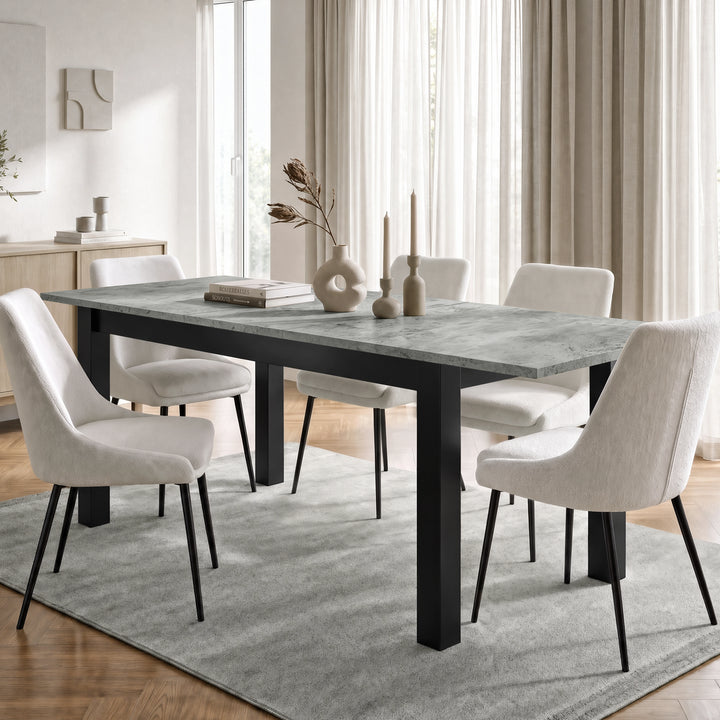 [160cm | Concrete] Extended table in bright dining room with six cream chairs, vases, candles, rug, and curtains