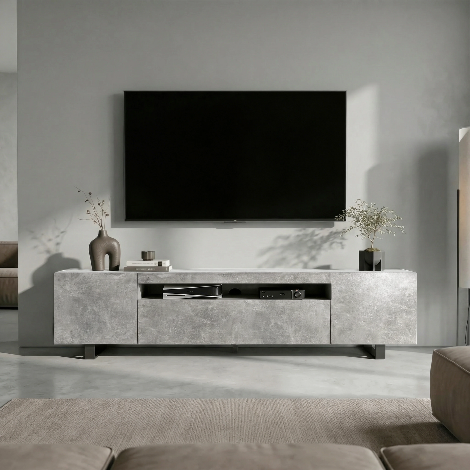 [Concrete] Kystra TV stand head-on under a large wall-mounted TV, two closed side cabinets flanking centre shelf