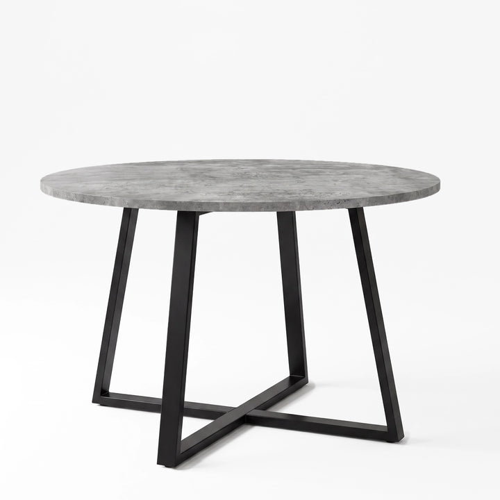 [Concrete] Round concrete-effect dining table in a studio view with the textured top resting on a black iron cross base.