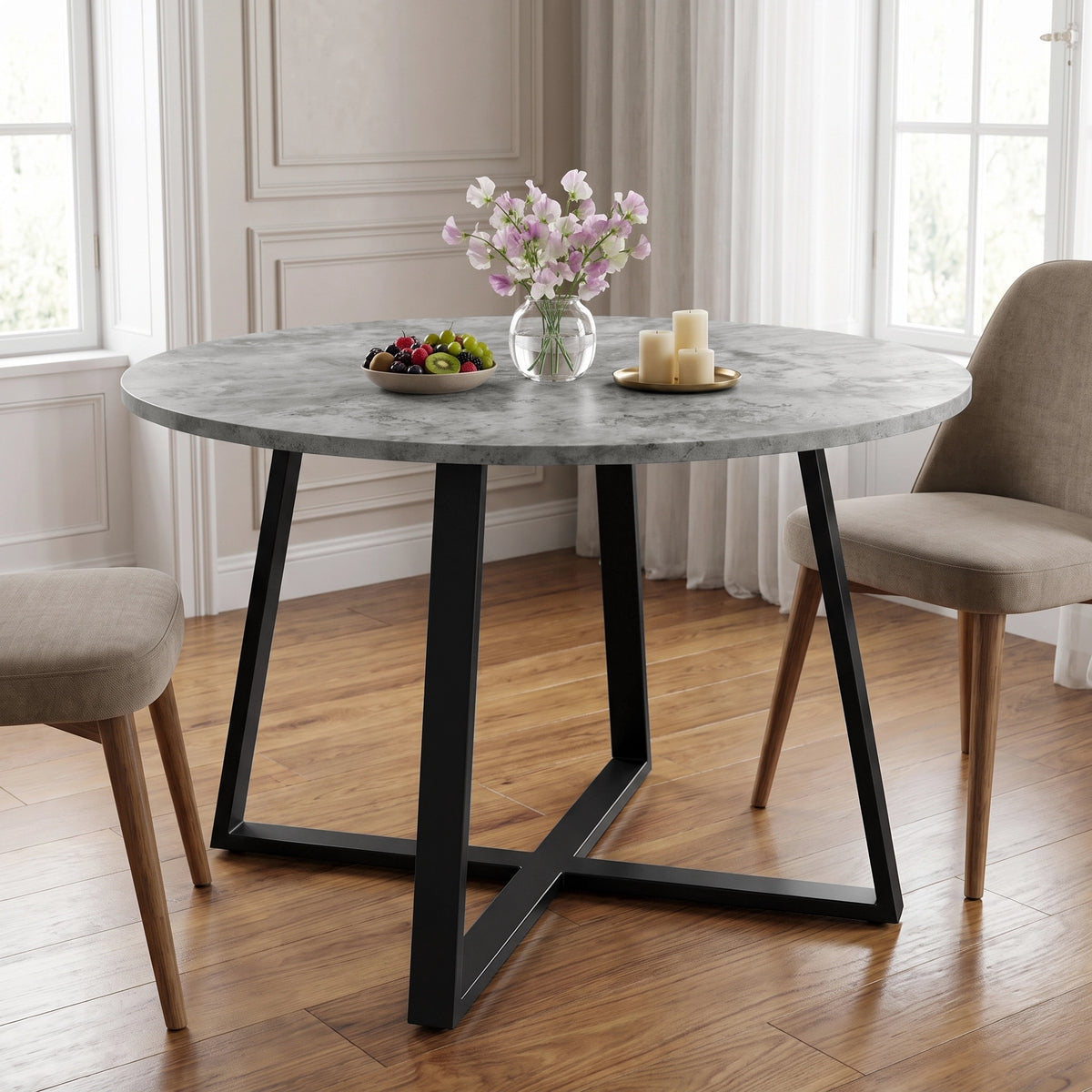 [Concrete] Round dining table in a bright room with flowers, fruit and candles on top between two chairs.