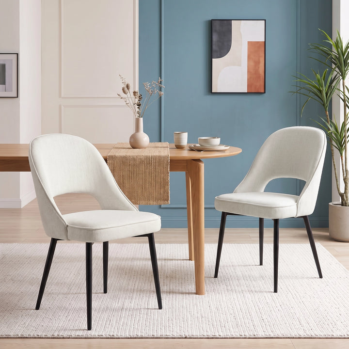 [Cream | Set of 2] Pair of curved-back dining chairs with piped seats and black legs arranged at a rectangular wood table.
