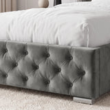 [Single | Grey] A gray tufted velvet bed frame with a white bedspread, shown in a softly lit bedroom setting with a textured rug and neutral decor.