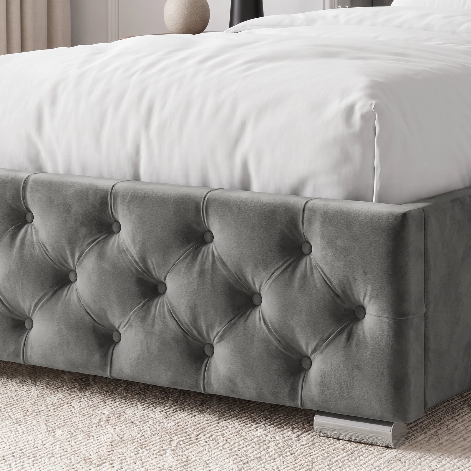 [Single | Grey] A gray tufted velvet bed frame with a white bedspread, shown in a softly lit bedroom setting with a textured rug and neutral decor.