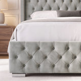 [King | Light Grey] A close-up of a bed frame with a light gray tufted velvet headboard and matching footboard, styled with white bedding and a gray pillow in a bedroom setting.