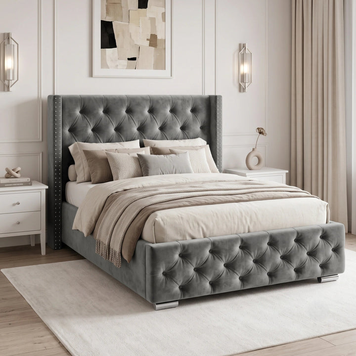 [Small Double | Grey] velvet bed frame with a high wingback headboard and matching footboard, styled in a modern bedroom with white nightstands, beige curtains, and wall sconces.