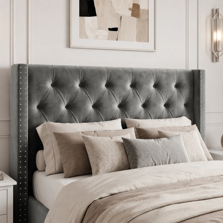 [Small Double | Grey] tufted velvet wingback headboard with silver nailhead trim, shown on a bed styled with neutral beige and gray bedding in a bedroom setting.