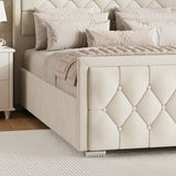 beige king ottoman bed with a cross-puffed footboard placed near a bedside table in a bedroom.