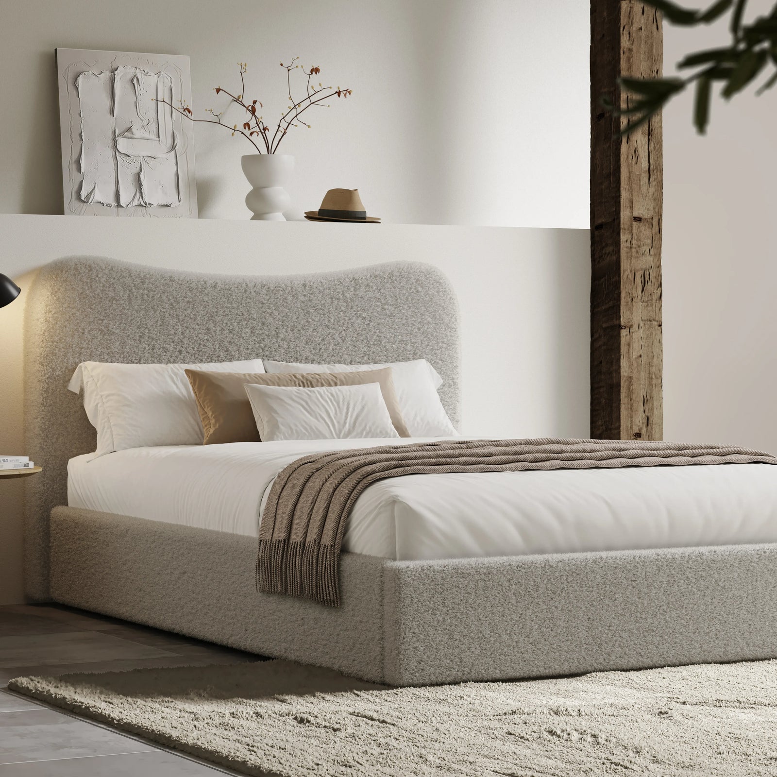 [King | Grey] Boucle fabric ottoman bed from the side with white bedding and fringed throw beside floating shelf with art