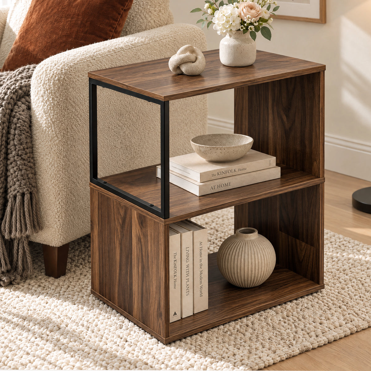 [Dark Bronx] This narrow side table stands beside a sofa with decor, books and a vase on its open shelves.
