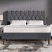 Gray upholstered bed with tufted headboard against a gray wall.