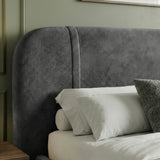 Close view of padded dark grey headrest with curved shape and fabric texture with light bedding