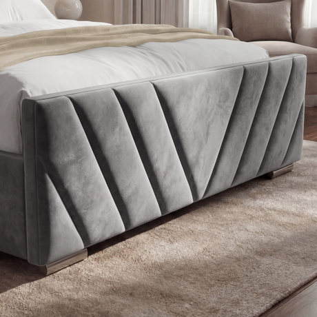 Footboard detail of a dark grey double ottoman bed frame with plush velvet fabric and v-shaped lines