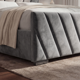 Close-up of the base of a dark grey ottoman bed showing the footboard structure and fabric cover
