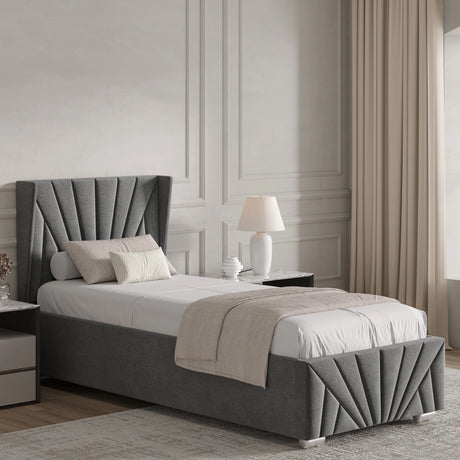 Grey upholstered bed in a bedroom with a lamp and decor items.