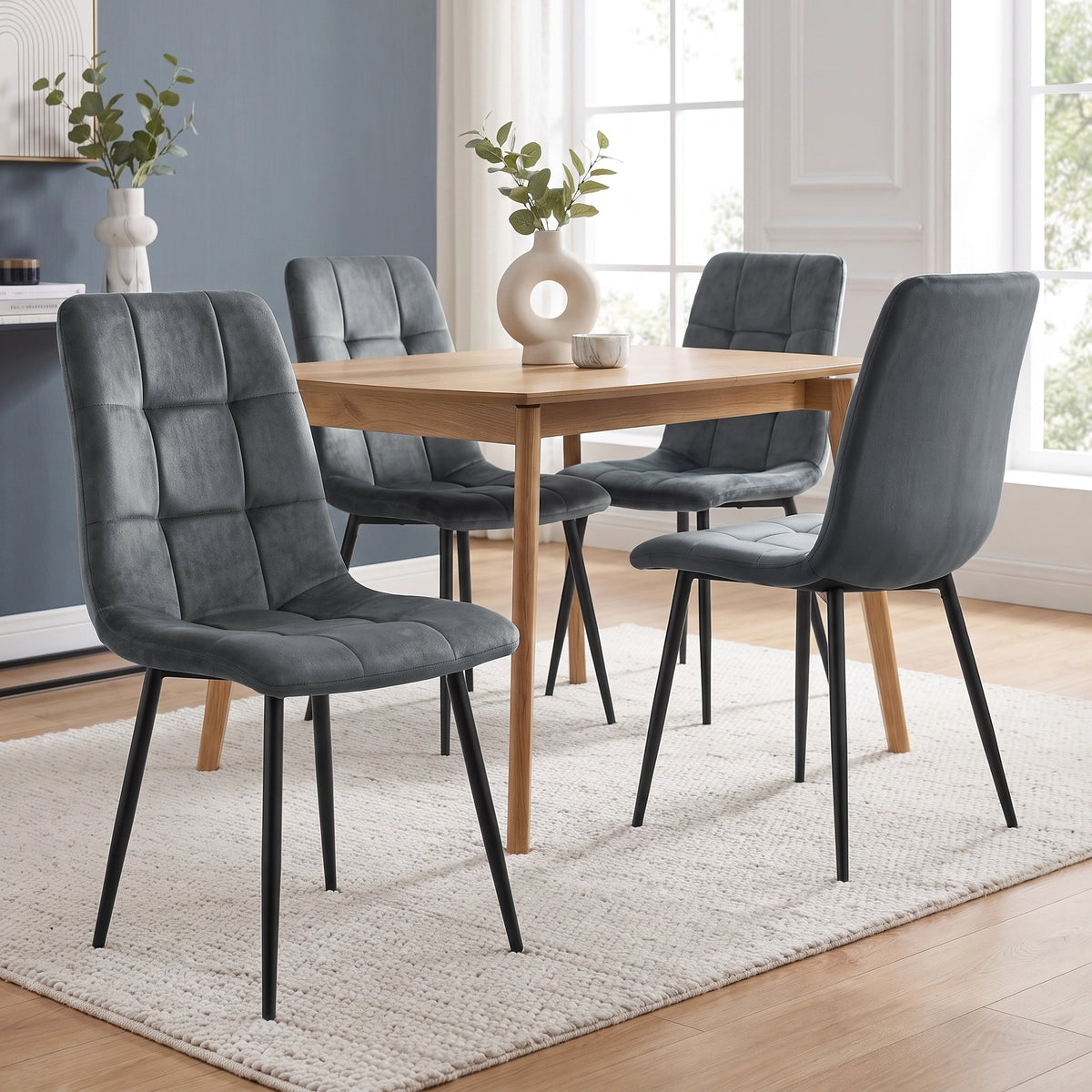 [Dark Grey | Set of 4] Velvet dining chairs at a rectangular wood-effect table, with tufted seats, curved backs and slim black legs.