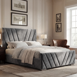 Dark grey velvet ottoman bed frame with v-design patterns, side view showing padded headboard in a modern room