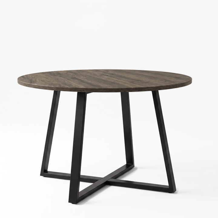 [Dark Wood] Round wood-effect dining table in a studio view with the tabletop resting on a black iron cross base.