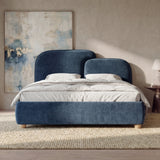 [Double | Blue] bed with gently split curved headboard and layered pillows arranged against a panelled wall