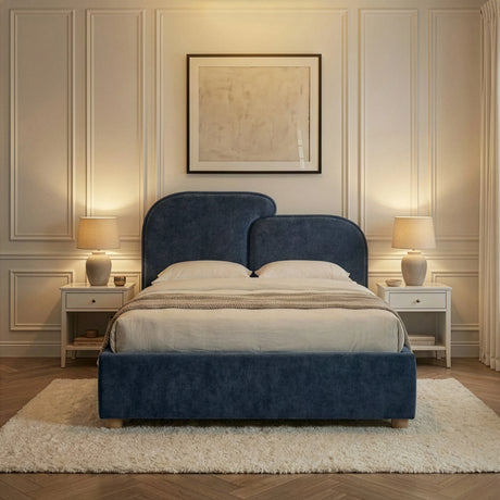 Blue double bed with gently split curved headboard and layered pillows arranged against a panelled wall