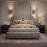 Fabric-covered sleeping double bed base with a cushioned backrest, layered neutral linens, and balanced ambient lighting