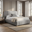 Soft grey fabric double bed with curved headboard in a neutral bedroom, angled side view
