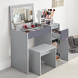 Small dressing table with flip-up mirror and stool in grey, featuring multiple storage compartments and drawers for makeup and beauty accessories.