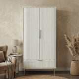 Freestanding white wardrobe with drawer placed in softly lit room with neutral walls and minimal decor