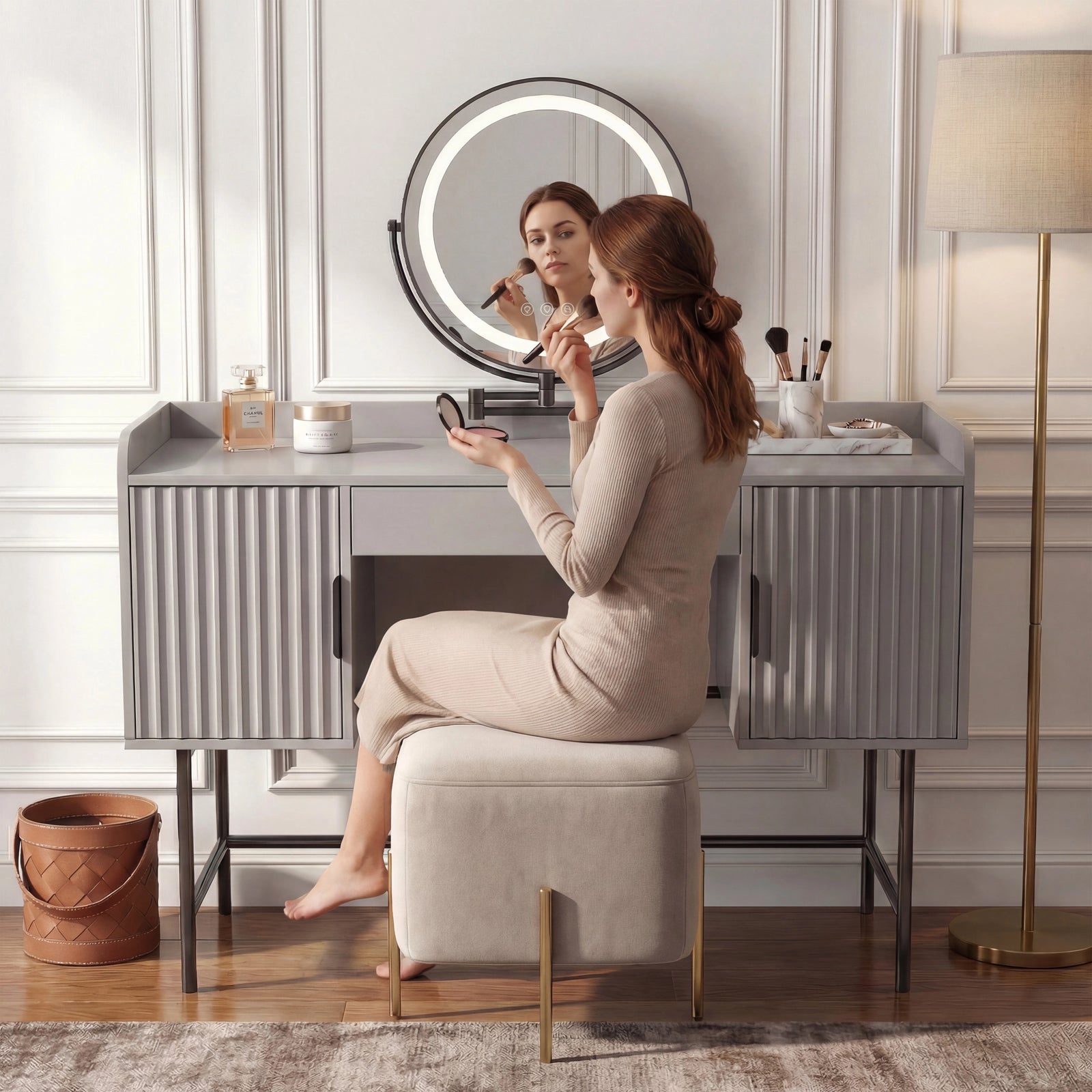 [Grey] side-profile lifestyle of the grey fluted vanity with a person at the white-lit round mirror and beige stool