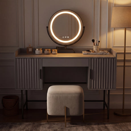 [Grey] side-profile lifestyle of the grey fluted vanity with a person at the white-lit round mirror and beige stool