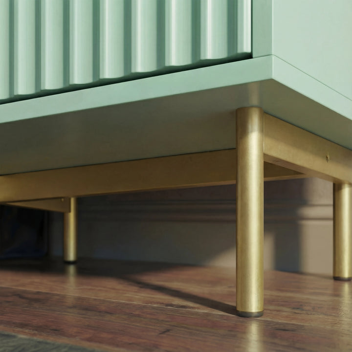 [Sage Green] bedside cabinet base corner with slim golden metal legs and elevated frame placed in a natural light space