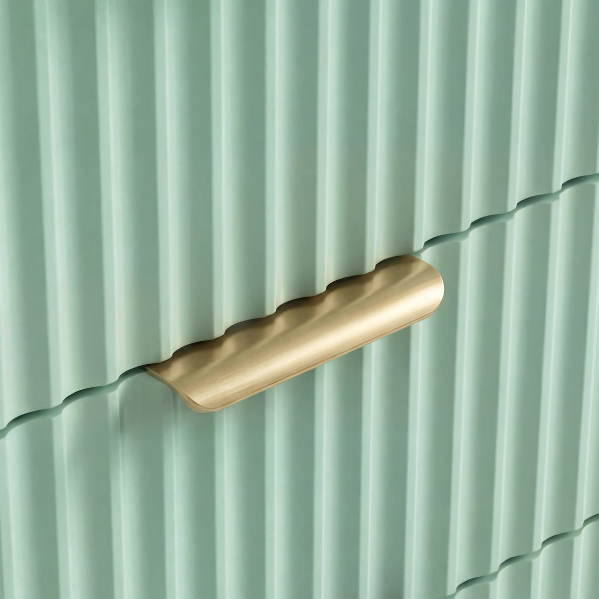 Close detail of golden metal handle on green flutrina drawer of chest front with vertical lines and stylish pattern