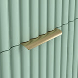 Close detail of golden metal handle on green flutrina drawer of chest front with vertical lines and stylish pattern