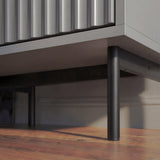 Grey bedside table bottom corner showing slim black metal legs and raised support placed in a natural lighting
