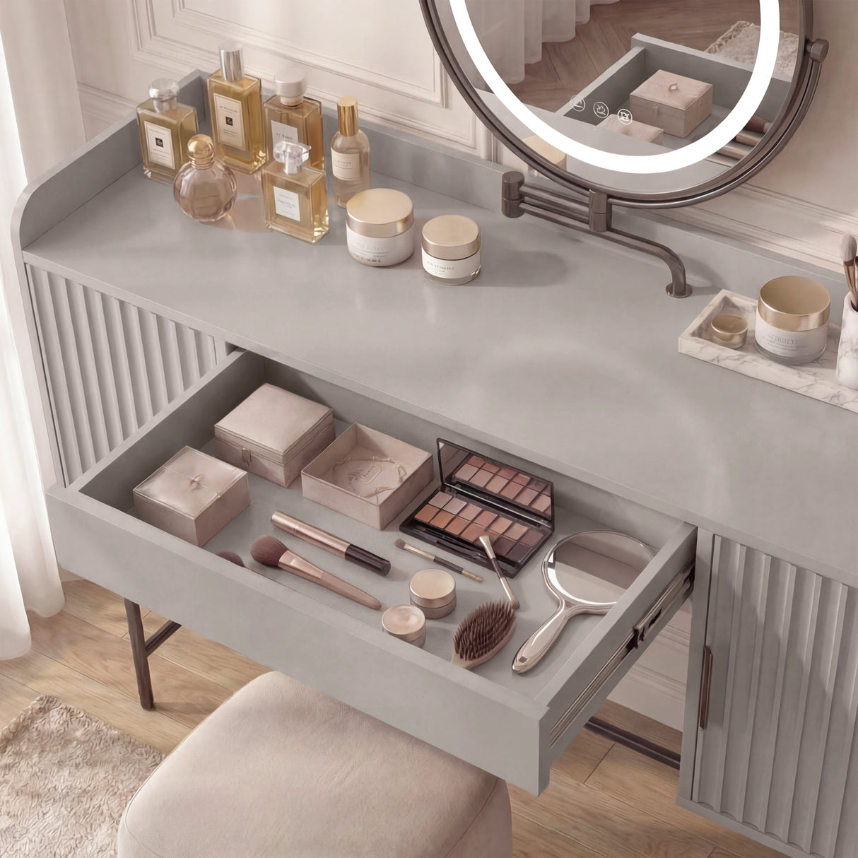 Grey vanity dressing table with a round mirror and an open drawer containing beauty products and accessories