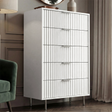 White painted 5 drawer chest with flutrina fronts and silver metal legs placed in a modern bedroom setting