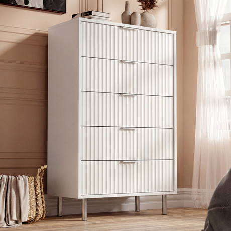 White painted 5 drawer chest with flutrina fronts and silver metal legs placed in a modern bedroom setting