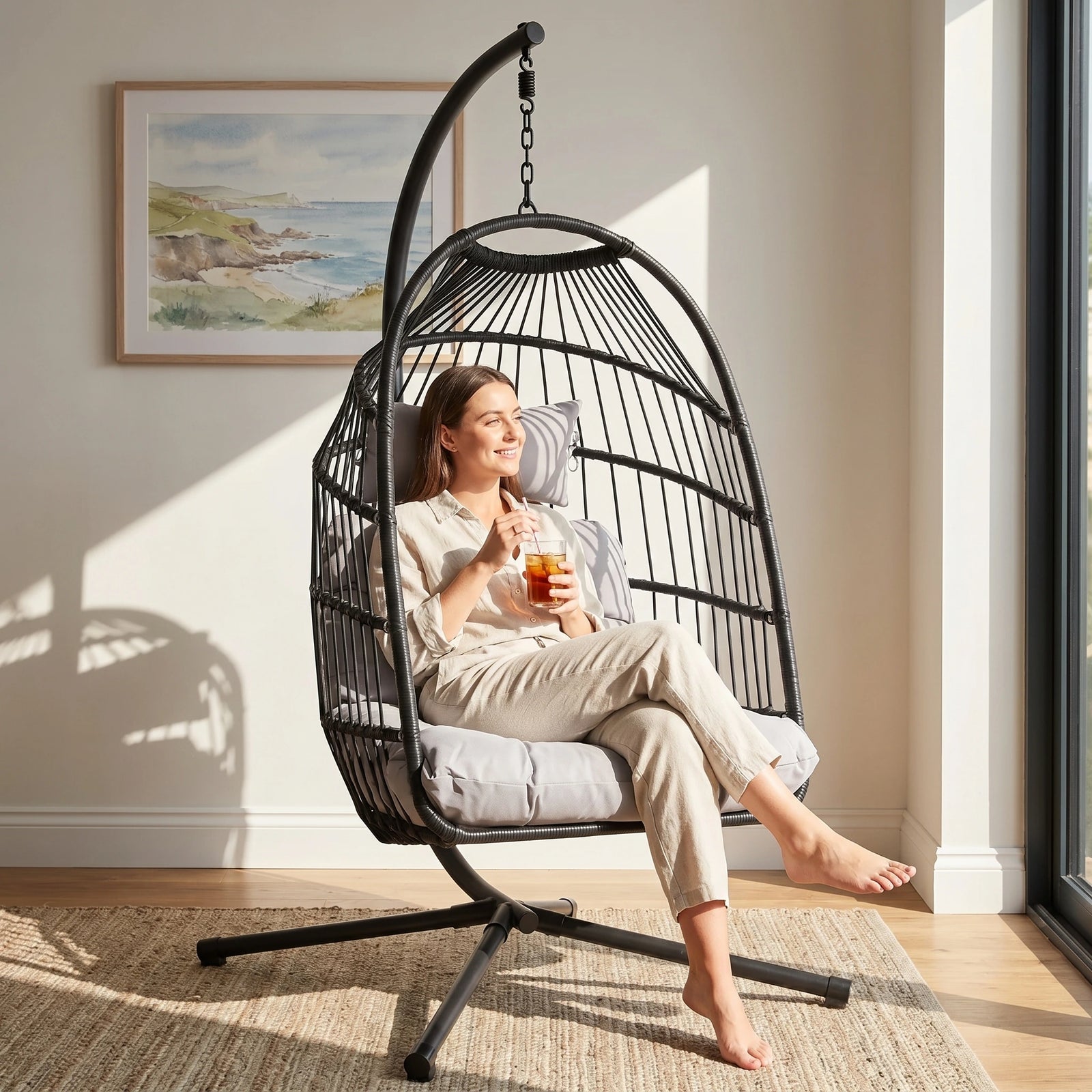 [Black] Black rattan garden egg chair with cushion in living space with a person relaxing on it