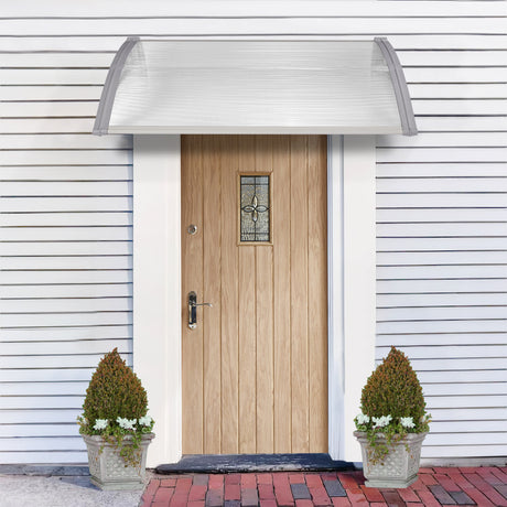 Front door with canopy a sleek grey, and decorative planters on a gray brick pathway.