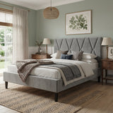 Neatly made bed in a bedroom with gray upholstered headboard, wooden nightstands, and decorative elements.