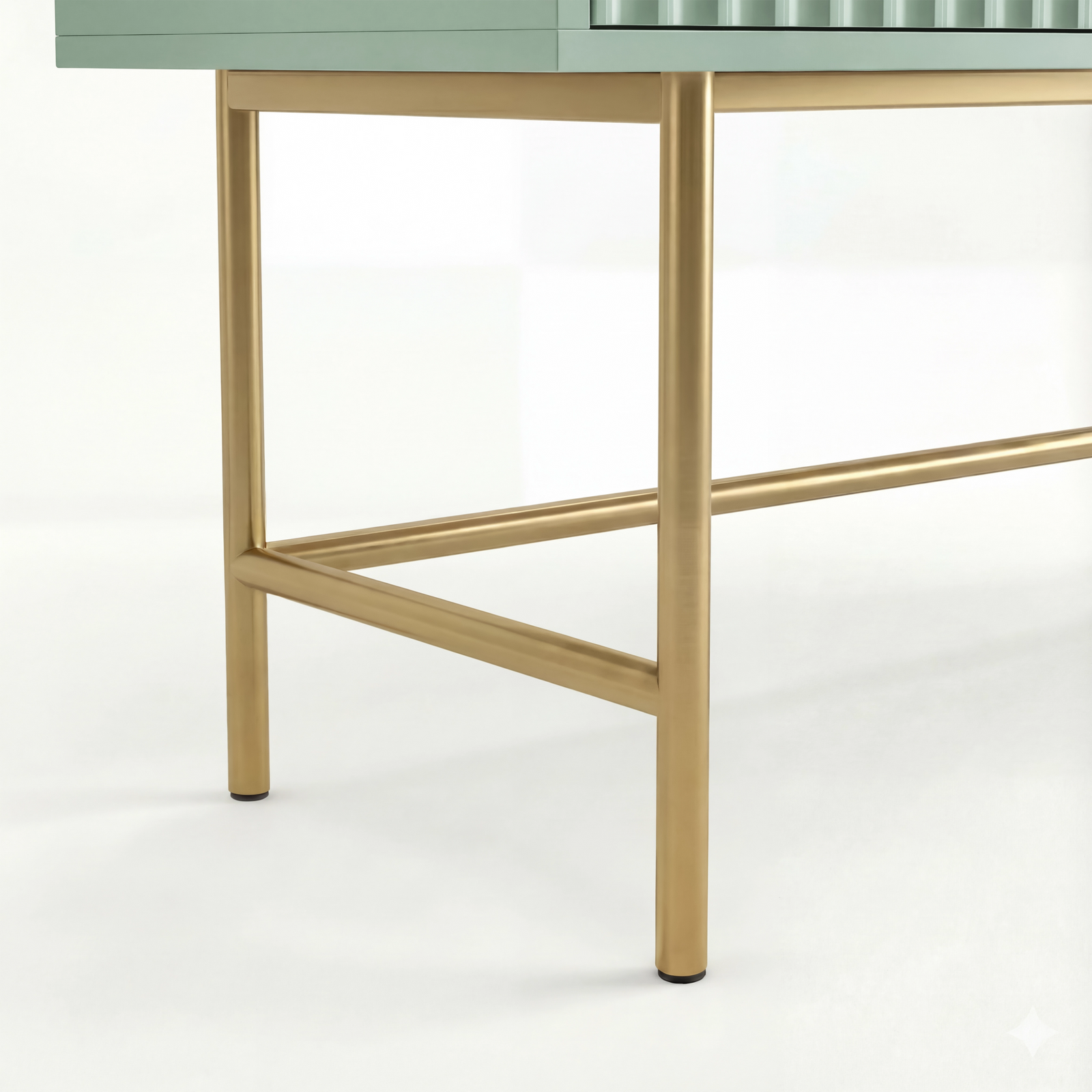 [Sage Green] close-up of two gold square-tube legs and a low gold stretcher beneath the sage green flutrina vanity