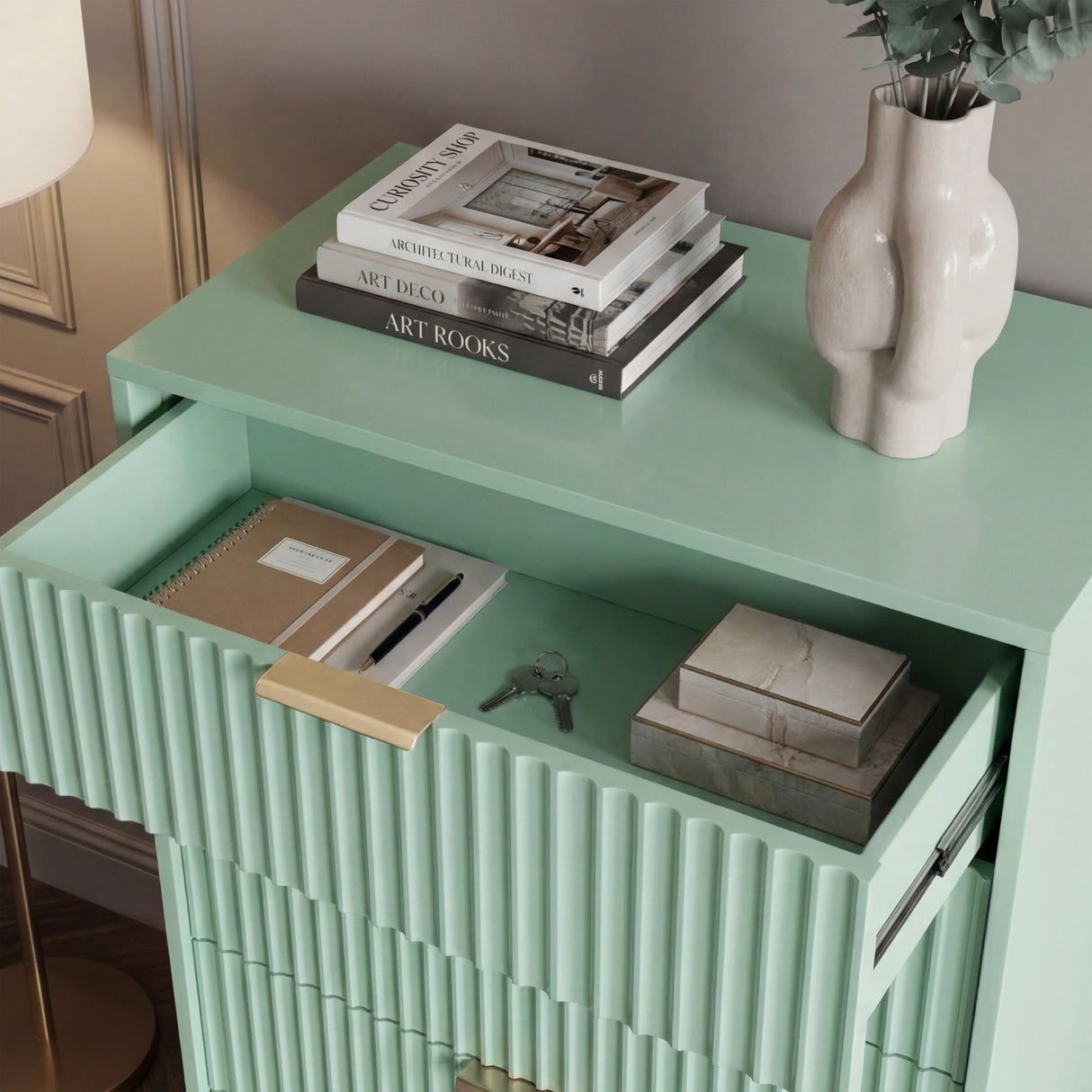 Green flutrina chest top surface styled with decor emphasizing painted finish with golden handles