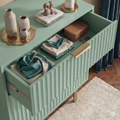 Interior drawer view of green painted chest displaying smooth storage compartment with golden metallic handles