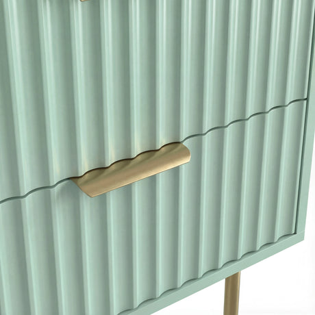 Close detail of the golden metallic handle fixed to the green flutrina design drawer surface of a nightstand