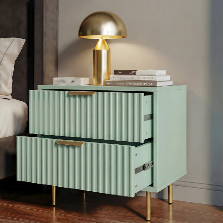 [Sage Green] nightstand with flutrina design, gold handles, and raised gold legs beside a bed with a lamp on top