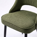 [Green | Set of 2] Comfy dining chair close-up of fabric seat, piped edge, curved open back and black metal legs.