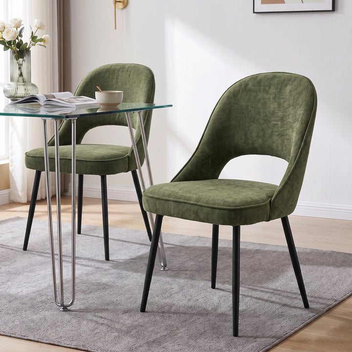 [Green | Set of 2] Pair of curved-back dining room chairs at a glass table styled with an open book, bowl & white rose vase.