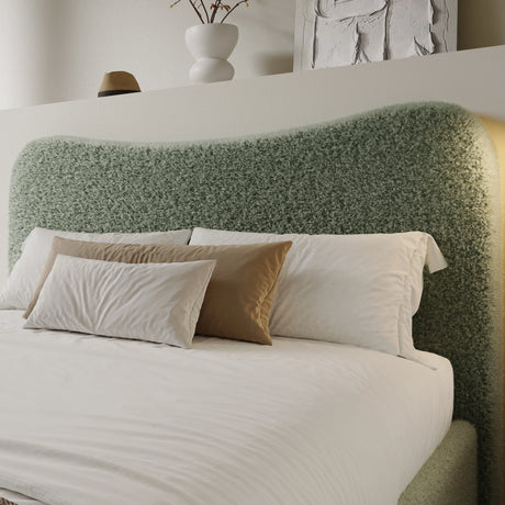 Curved headboard ottoman storage bed in light green boucle fabric with plush pillows. Stylish platform bed frame with hidden under-bed storage.